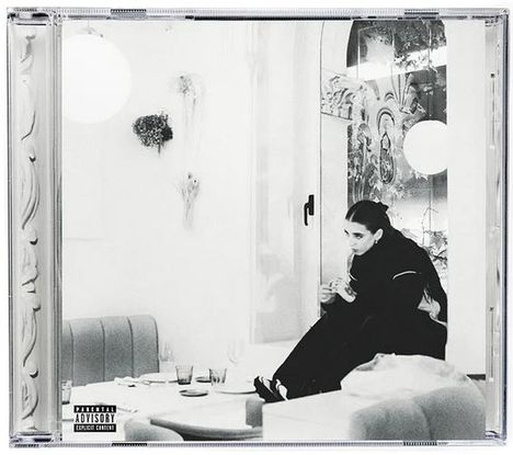 Schwarz-weiß, sitzende Person in einem eleganten Raum. Links unten ein "Parental Advisory" Hinweis.