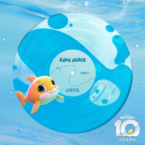 Text: "Baby Shark", "Side A", "10 Years of Fun and More to Come". Illustration: Gelber Hai und blaue Vinyl-Schallplatte.
