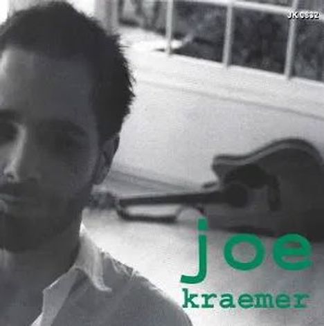 Text: "joe kraemer". Ein unscharfer Mann im Vordergrund, Gitarre im Hintergrund, schwarz-weiß.