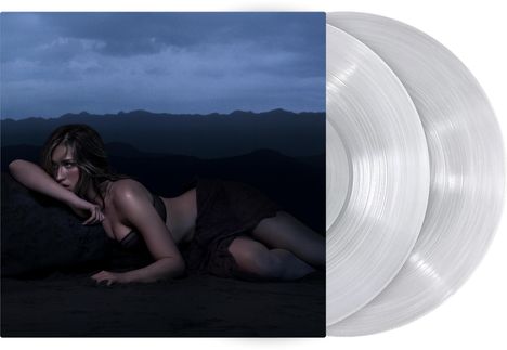 Kein lesbarer Text. Eine Frau liegt in dunkler Umgebung; es gibt zwei transparente Schallplatten rechts.