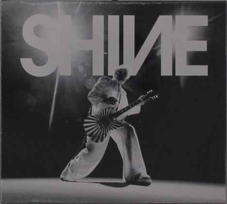 Der Text "SHINE" ist groß und markant. Unten ist eine Person in weiß, die eine Gitarre mit auffälligem Muster spielt.