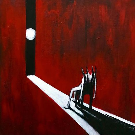 Eine Person sitzt auf einem Stuhl in einem dunklen Raum. Rotes Licht und ein enger Lichtstrahl lenken den Blick auf die Szene.