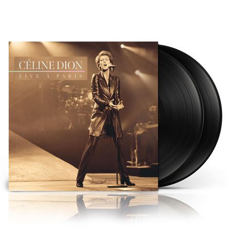 "CÉLINE DION LIVE À PARIS" steht auf einem Albumcover. Im Hintergrund singt eine Frau in einem langen Mantel auf der Bühne.
