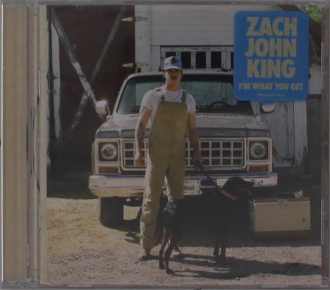 Ein Mann in Latzhose steht vor einem alten Auto. Rechts oben steht: "ZACH JOHN KING I'M WHAT YOU GET". Ein Hund ist an der Leine.