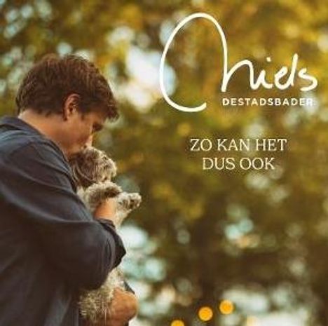 „Niels Destadsbader“ und „Zo kan het dus ook“. Ein Mann hält einen kleinen Hund im Arm vor unscharfem Hintergrund.