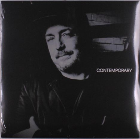 Text: "CONTEMPORARY". Schwarz-weiß Porträt eines Mannes mit Bart und Mütze, der leicht lächelt.