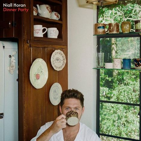 "Niall Horan Dinner Party" ist links oben geschrieben. Eine Person trinkt aus einer gemusterten Tasse in einer Küche.