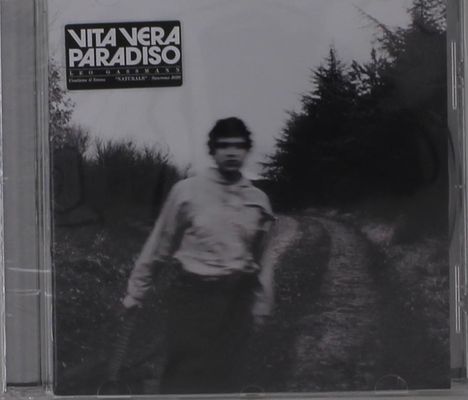 Aufschrift: "VITA VERA PARADISO". Darunter unscharfe Abbildung eines Mannes auf einem Waldweg.