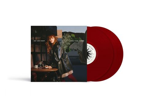 "DAY AND NIGHT", "CARLY RAE JEPSEN". Frau in dunklem Mantel an Tisch, rote Schallplatten daneben.