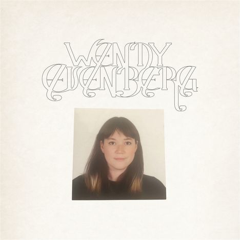 Der Text "WANDY LUSENBERG" in geschwungener Schrift über einem Foto einer Frau mit dunklem Haar und hellem Hintergrund.