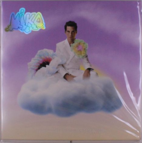 Oben links steht „MIKA“ in bunten Buchstaben. Ein Mann im weißen Anzug sitzt auf einer Wolke vor einem lila Himmel.