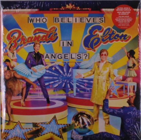 "Who believes in angels?" Vor einem bunten, leuchtenden Hintergrund mit zwei Personen in extravaganten Outfits.