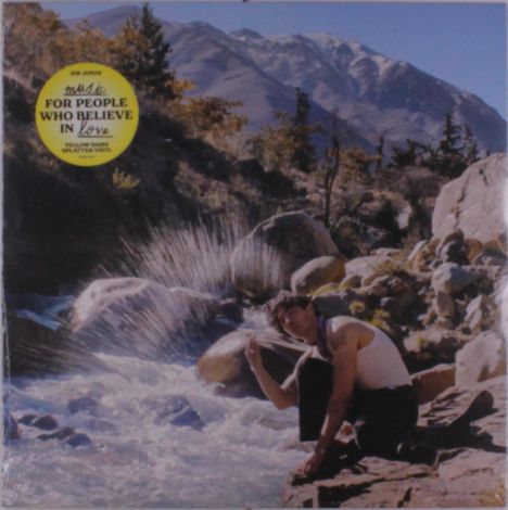 Gelber Kreis: "For people who believe in love". Ein Mann hockt am Fluss, umgeben von Felsen. Berge im Hintergrund.