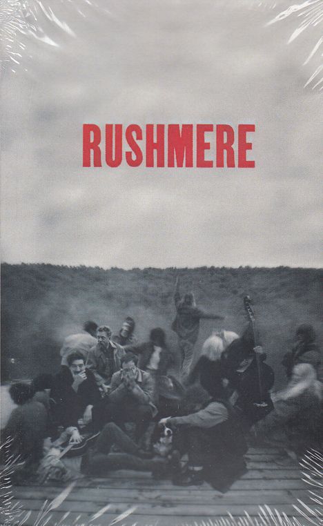 "RUSHMERE" in roter Schrift oben; darunter eine unscharfe Szene mit Menschen auf einer Plattform; eine Gitarre ist erkennbar.