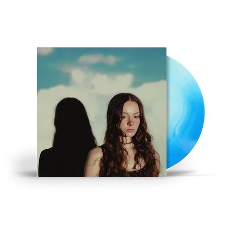 Keine Texte sichtbar. Frau mit langen Haaren vor bewölktem Himmel; blauer Vinyl-Schallplattenrand sichtbar.