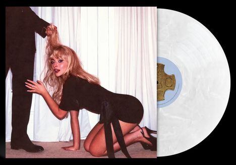 Es gibt keinen klaren Text im Bild. Eine Frau kniet auf dem Boden und jemand außerhalb des Blickfelds hält ihr Haar. Rechts ist eine Schallplatte.