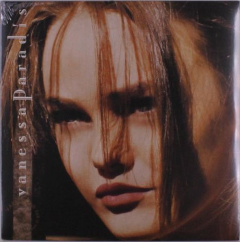Text: "vanessa Paradis" vertikal. Nahaufnahme einer Frau mit langen braunen Haaren, die ins Gesicht fallen.