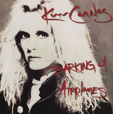 Oben steht „Kim Carnes”, unten „Barking at Airplanes”. Eine Person mit langem, blondem Haar blickt ernst.