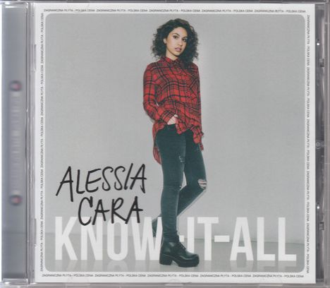 "Alessia Cara" und "Know-It-All" Text in großen Buchstaben. Junge Frau in Hemd und Jeans steht lässig vor grauem Hintergrund.