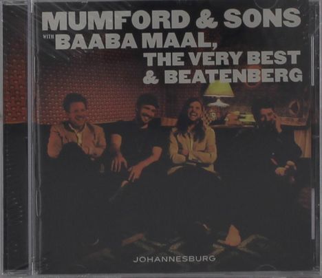 MUMFORD & SONS, BAABA MAAL, THE VERY BEST & BEATENBERG. Vier Personen sitzen lächelnd auf einem Sofa in warmem Licht.