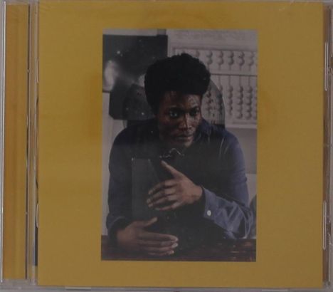 Ein Cover in Gelb mit einer mittigen Fotografie. Darauf ein Mann in einem dunklen Hemd, der mit den Händen gestikuliert.