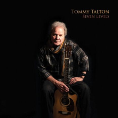 Tommy Talton, Seven Levels. Eine Person sitzt mit einer Gitarre, trägt kariertes Hemd und Schal, vor einem dunklen Hintergrund.