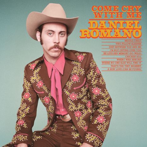 Cover mit gelbem und orangefarbenem Text: "COME CRY WITH ME, DANIEL ROMANO". Person im Cowboy-Outfit.