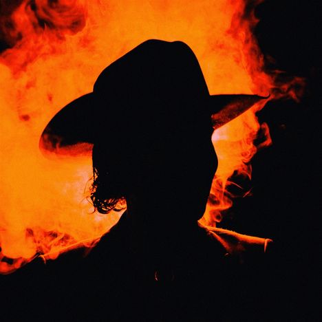 Keine erkennbaren Texte. Silhouette einer Person mit Hut vor leuchtend rotem Hintergrund.