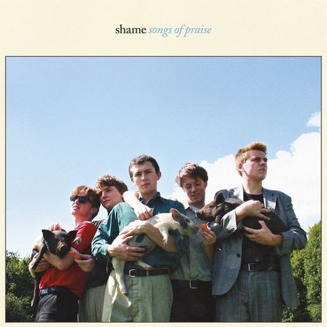 Oben steht "shame songs of praise". Fünf junge Männer halten Ferkel auf einer Wiese unter einem blauen Himmel.