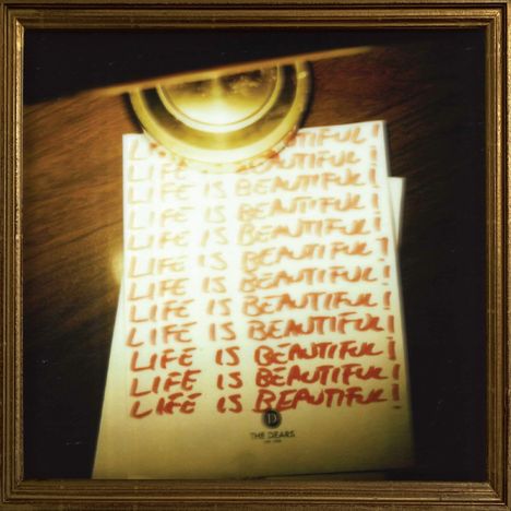 Wiederholter Text "LIFE IS BEAUTIFUL!" in roter Schrift auf Papier unter einer Lampe, eingerahmt.
