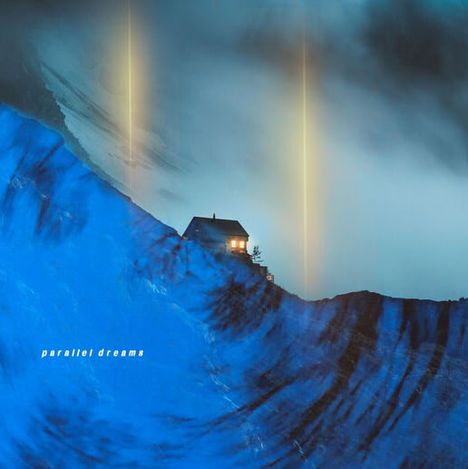 Text: "parallel dreams". Ein beleuchtetes Haus auf einem blauen Abhang, mit leuchtenden Säulen im Hintergrund.