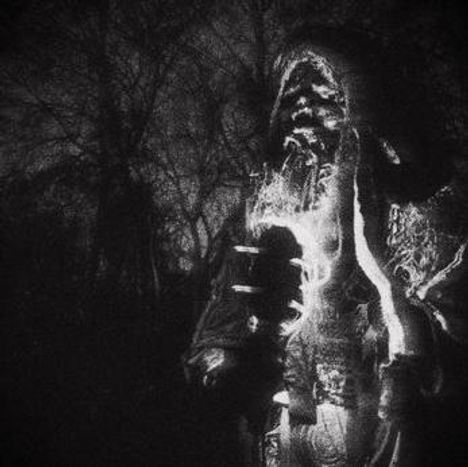 Es sind keine Texte im Bild zu sehen. Eine schwarz-weiße Nachtszene zeigt eine mystische Figur im Mantel vor kahlen Bäumen.