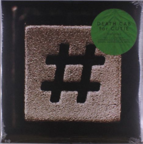Grüner Kreis mit Text: "DEATH CAB for CUTIE". Abgebildet ist eine Nahaufnahme einer metallischen Raute.