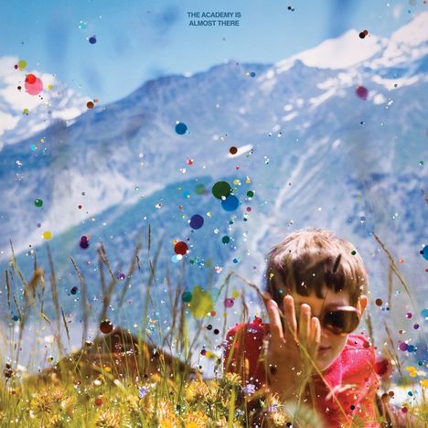 Der Text lautet: "THE ACADEMY IS ALMOST THERE." Ein Kind in der Natur mit Sonnenbrille, bunte Punkte schweben in der Luft.