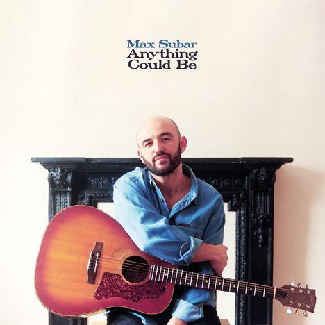 Oben steht "Max Subar Anything Could Be". Eine Person sitzt mit einer Gitarre vor einem Kamin.