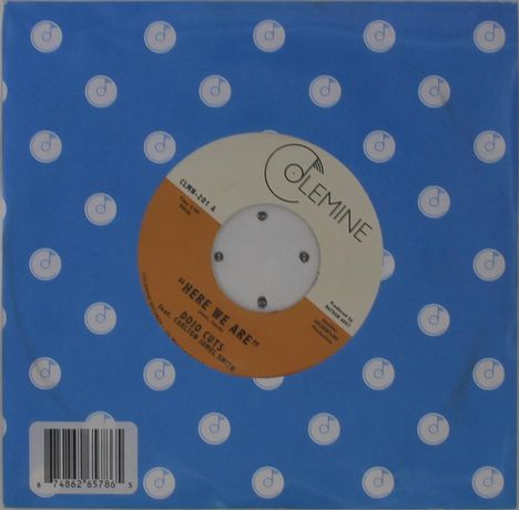 Aufdruck: "Here We Are", Dojo Cuts. Oben: "Colemine". Schallplatte mit blauem Hintergrund voller kleiner Kreise mit „d“-Symbol.