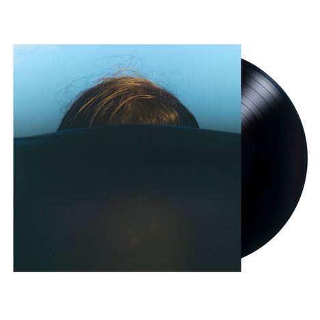 Ein Vinyl-Schallplatten-Cover, das einen Kopf zeigt, der hinter einer dunklen Fläche hervorragt, vor einem blauen Himmel.