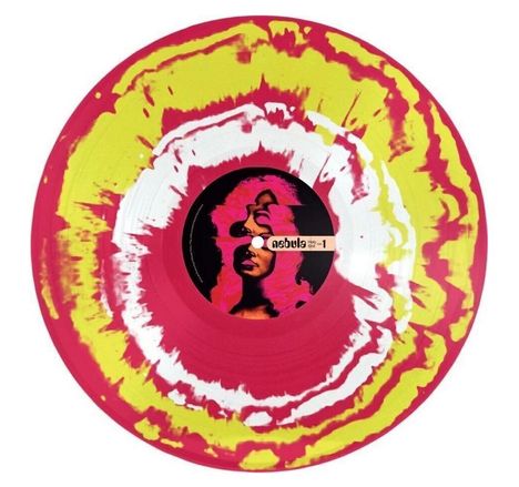 Text: "nebula Holy Shit 1". Bunt marmorierte Schallplatte mit gelben, pinken und weißen Wirbeln. Zentrales Bild einer Person.