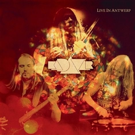 "Live in Antwerp" ist zu lesen. Drei Musiker spielen Instrumente. Im Hintergrund sind bunte, kaleidoskopartige Muster.