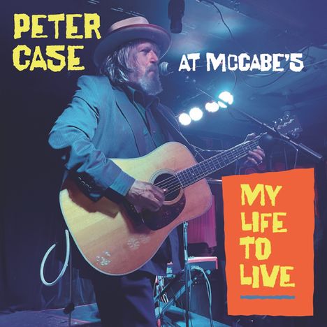 "Peter Case at McCabe’s", "My Life to Live". Eine Person spielt Gitarre auf einer Bühne mit Mikrofon, trägt Hut und Jacke.