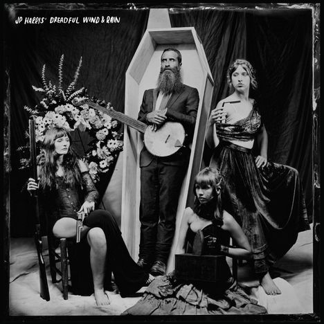 Texte: "JP Harris' Dreadful Wind & Rain". Eine Schwarz-Weiß-Aufnahme zeigt vier Personen, eine im Anzug mit Banjo, andere in eleganter Kleidung.