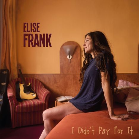 „Elise Frank“ oben links, „I Didn't Pay For It“ unten rechts. Eine Frau sitzt auf einem Bett, im Hintergrund eine Gitarre.