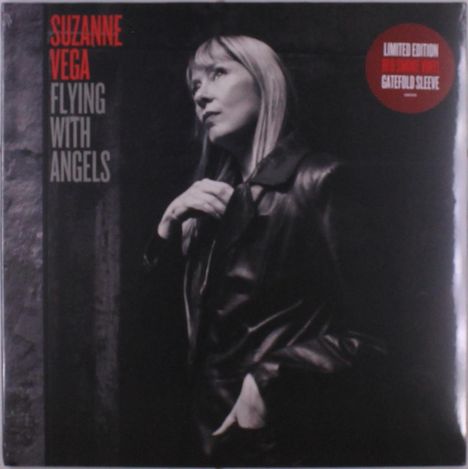 „SUZANNE VEGA FLYING WITH ANGELS“ auf dunklem Hintergrund, Frau in Lederjacke blickt nachdenklich.