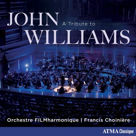 „JOHN WILLIAMS: A Tribute to“, „Orchestre FILMharmonique | Francis Choinière“. Konzertsaal mit Orchester in blauem Licht.