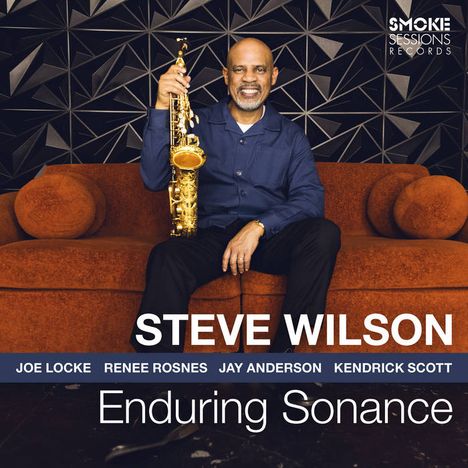 "STEVE WILSON", "Enduring Sonance". Ein Mann sitzt mit Saxophon auf einem orangefarbenen Sofa vor einem geometrischen Wandmuster.