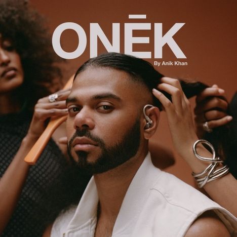 "ONĒK - By Anik Khan" steht oben. Eine Person mit Bart sitzt, während zwei Hände ihr die Haare machen.