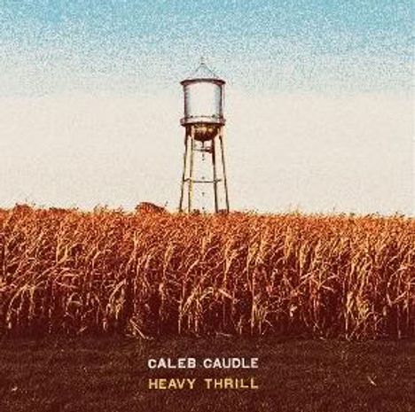 "CALEB CAUDLE HEAVY THRILL" steht vor einem Wasserturm über einem Feld mit hohem, goldenen Gras unter blauem Himmel.