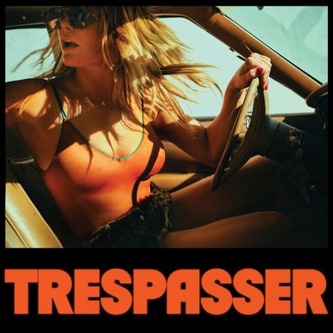 "TRESPASSER" in großen orangefarbenen Buchstaben; eine Frau mit Sonnenbrille fährt ein Auto.