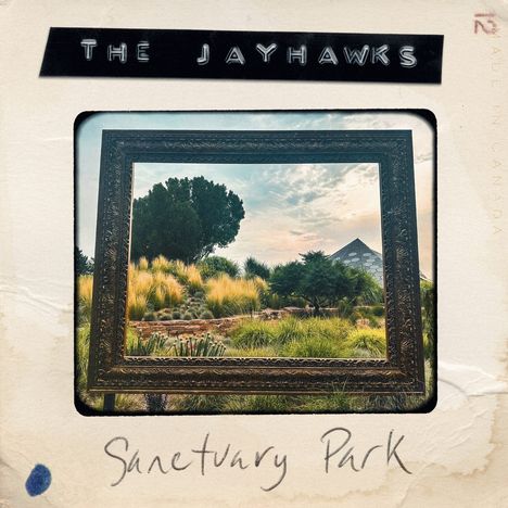 "The Jayhawks" und "Sanctuary Park". Ein Gemälde eines Parks mit Bäumen und Gräsern, eingefasst in einen Bilderrahmen.
