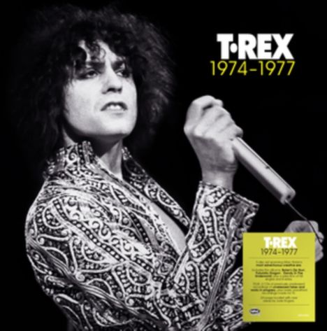 T.REX 1974-1977. Schwarz-weißes Foto eines Mannes mit lockigem Haar und gemustertem Jackett, der ein Mikrofon hält.